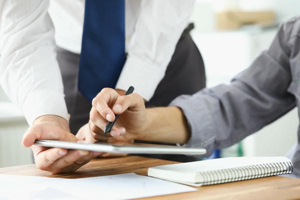 arbeitsbedingungen-digitale-arbeitsvertraege Zwei Arbeitskollegen schauen sich zusammen digitale Arbeitsverträge auf einem Tablet an.