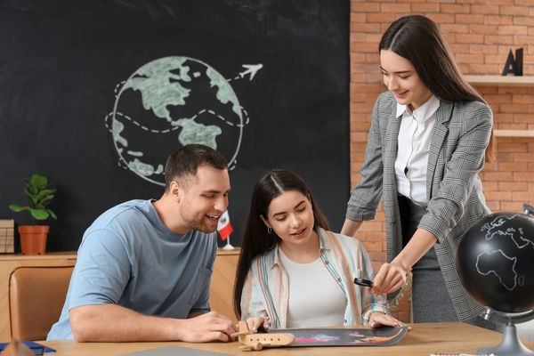 arbeitsleben-bildungsurlaub-im-ausland 3 junge Menschen, die gemeinsam an etwas arbeiten und sich austauschen im Hintergrund ist ein Globus an die Tafel gezeichnet worden
