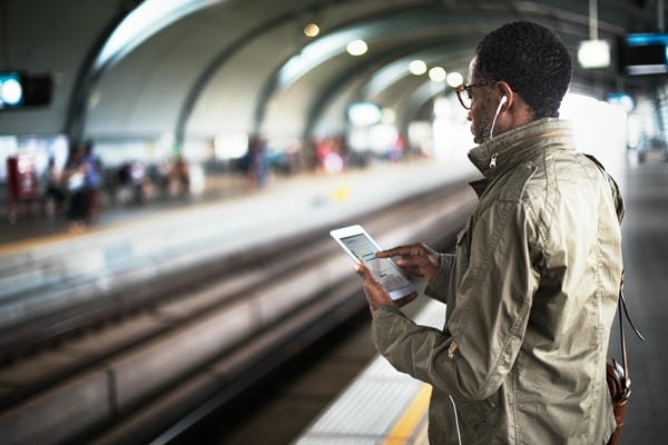 Pendlerpauschale in Deutschland Man wartet am Bahnhof mit Tablet in der Hand