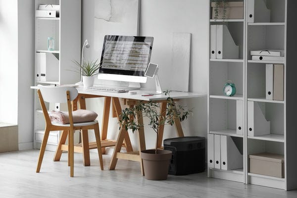 Ein Arbeitsplatz mit Schreibtisch, Monitor, Stuhl und Dekoration.