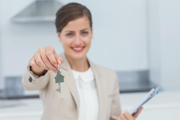 berufsinformationen-immobilienmakler Eine Immobilienmaklern hält einen Schlüssel in die Kamera.