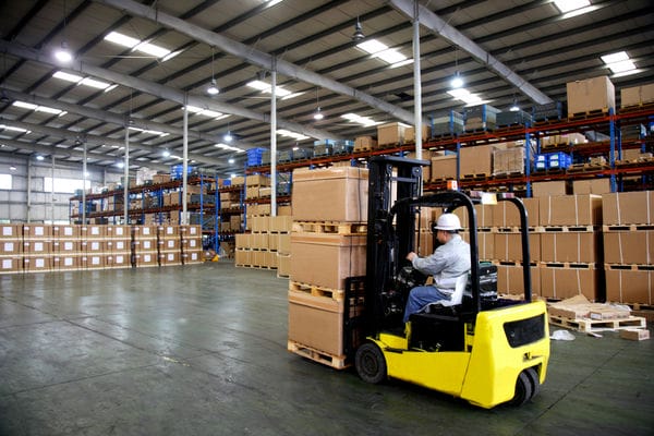 karriere-karriere-in-der-logistik Ein Mann fährt Ware mit einem Gabelstapler durch ein Lager.