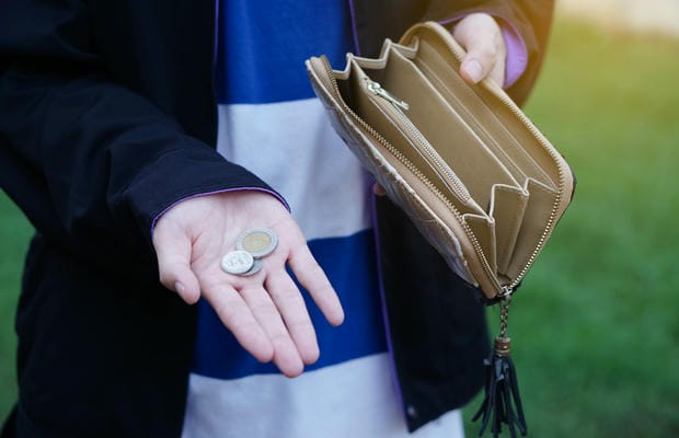 verguetung-netto Eine Person blickt enttäuscht auf die wenigen Münzen in ihrer Hand, während das geöffnete Portemonnaie nach Abzug aller Kosten komplett leer ist – ihr bleibt kaum Netto vom Brutto.
